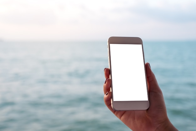 Makieta inteligentny telefon z ręki ludzi nad morzem