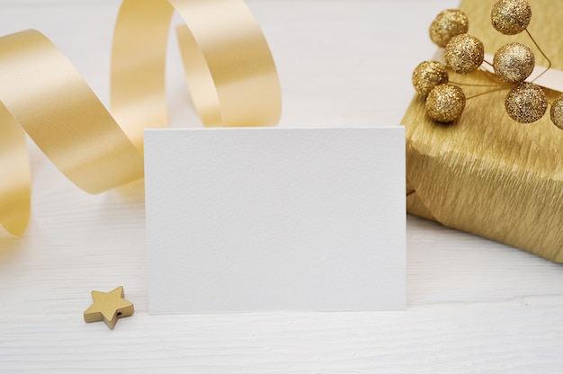 Makieta Kartki świąteczne Pozdrowienia Ze Złota Wstążka Prezent, Flatlay Na Białym Tle Drewnianych