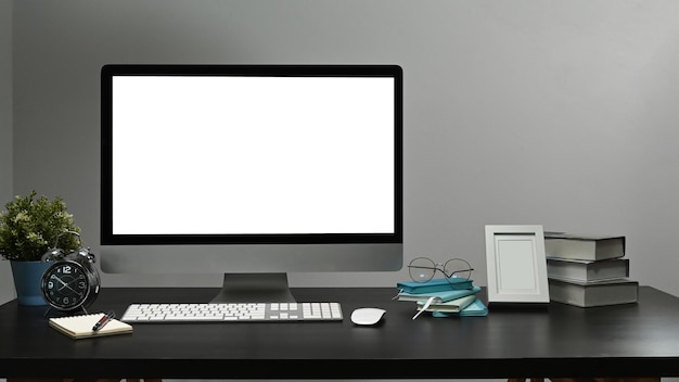 Zdjęcie makieta komputera pc z białym wyświetlaczem budzik doniczkowy i ramka na zdjęcia na czarnym stole