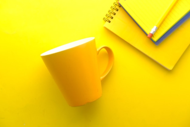 Zdjęcie makieta kubka w kolorze żółtym z zeszytami na żółto