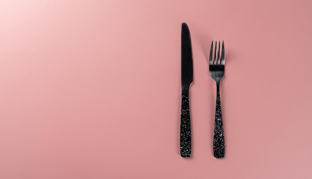 Makieta noża i widelca na różowym tle stołu