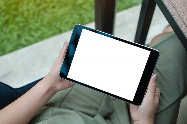 Makieta obraz kobiety ręce trzymając czarny tablet PC z białym pustym ekranem siedząc w kawiarni