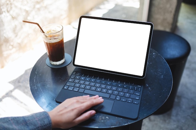 Makieta obraz kobiety używającej i dotykającej touchpada tabletu z pustym białym ekranem pulpitu jako komputer PC z filiżanką kawy na stole