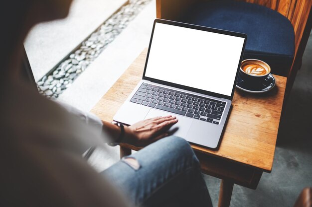 Makieta obrazu bizneswoman używającej i dotykającej touchpada laptopa z pustym białym ekranem pulpitu w kawiarni