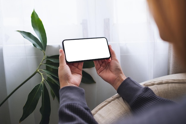 Makieta obrazu kobiety trzymającej telefon komórkowy z pustym ekranem pulpitu w domu