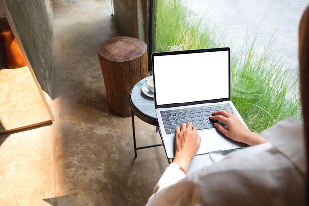 Makieta obrazu kobiety używającej i piszącej na komputerze przenośnym z pustym białym ekranem pulpitu w kawiarni