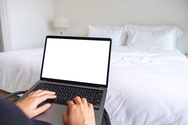 Makieta obrazu kobiety używającej i piszącej na laptopie z pustą białą klawiaturą ekranową pulpitu w sypialni