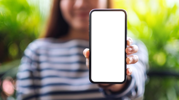 Makieta obrazu pięknej azjatyckiej kobiety trzymającej i pokazującej telefon komórkowy z pustym białym ekranem