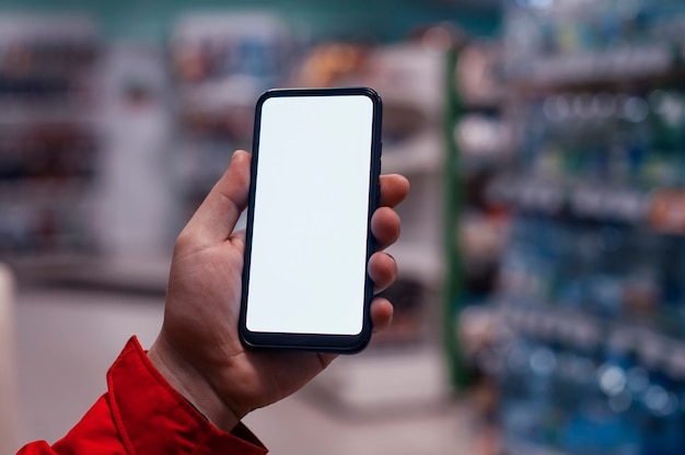 Makieta smartfona z białym ekranem w rękach mężczyzny. Telefon na przestrzeni gablot w sklepie.