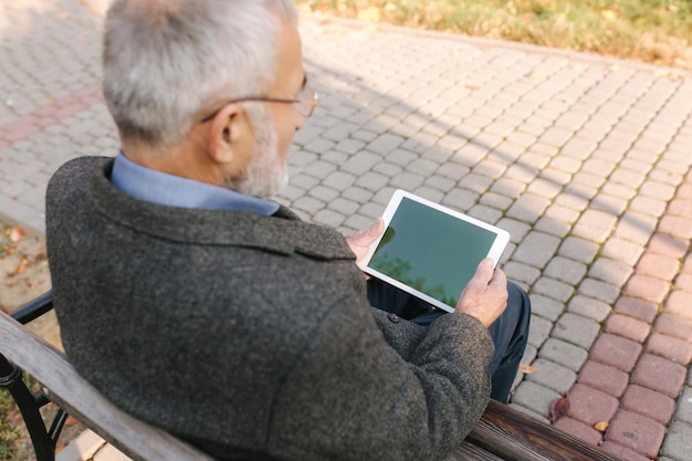 Makieta Starszego Mężczyzny Używającego Tabletu Na Zewnątrz Widok Z Tyłu Starszego Mężczyzny Siedzącego Na ławce I Używającego