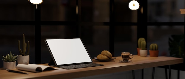 Makieta tabletu z widokiem z boku z klawiaturą na stole przy oknie w nowoczesnej kawiarni na poddaszu w nocy