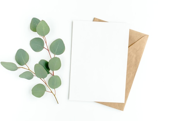Makieta zaproszenia pusta kartka z życzeniami i zielone liście eukaliptusa Płaski widok z góry