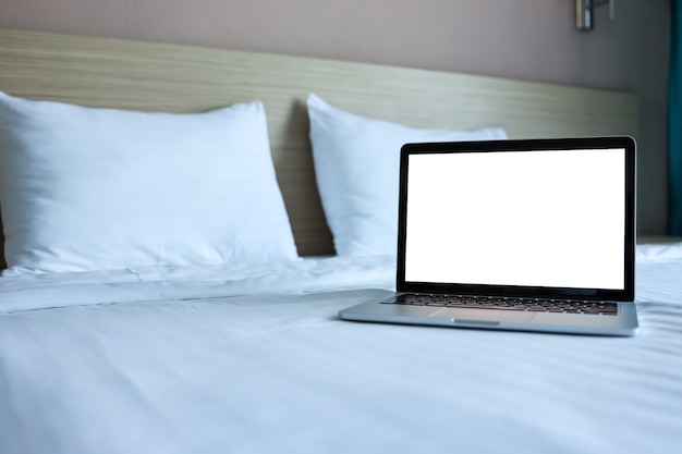 Makiety laptopa z pustym ekranem na łóżku na reklamy i tekst.