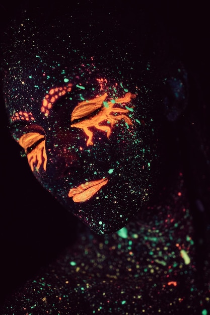 Makijaż ultrafioletowy. Portret dziewczynki namalowany proszkiem fluorescencyjnym. Koncepcja Halloween.