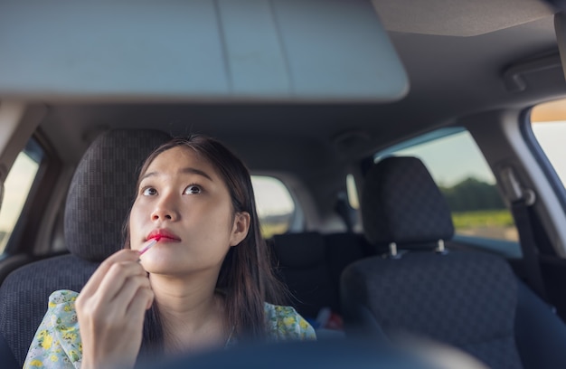 Makijaż w samochodzie, młoda kobieta nakładająca makijaż podczas jazdy