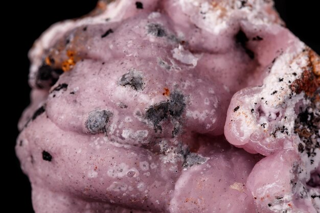 Zdjęcie makro różowy kamień mineralny smithsonite na mikroklinie na czarnym tle