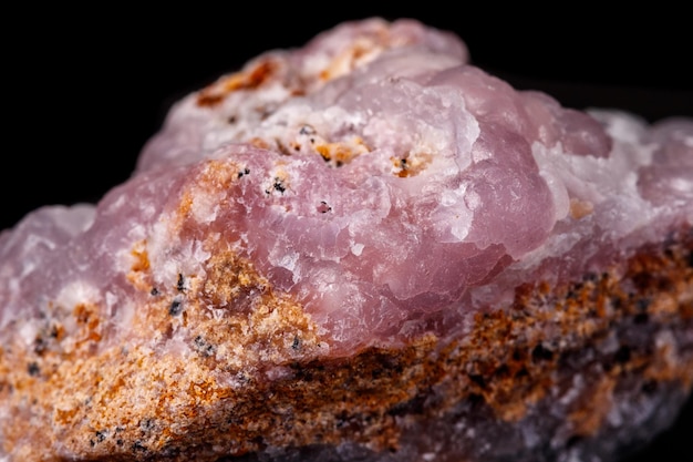 Makro różowy kamień mineralny Smithsonite na mikroklinie na czarnym tle