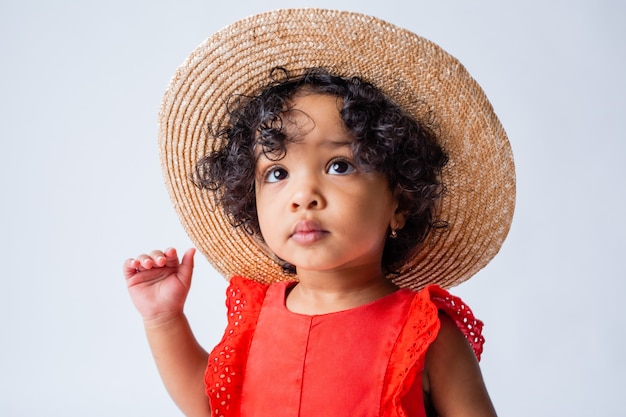 mała Afroamerykanka w czerwonych letnich ubraniach i słomkowym kapeluszu na białym tle w studio