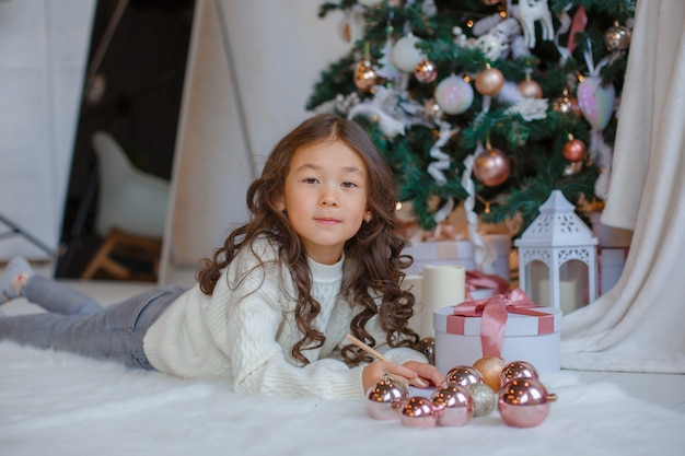 Mała Azjatka pisze list do Świętego Mikołaja przy choince, uśmiecha się Boże Narodzenie, nowy rok