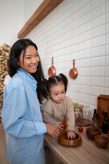 Zdjęcie mała azjatycka dziewczynka spędzająca czas w domu w kuchni z matką