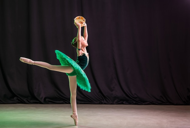 Mała baletnica tańczy na scenie w tutu na pointach z tamburynem, klasyczną odmianą Esmeraldy.