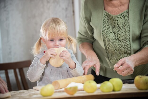 Mała blondynka o niebieskich oczach gryzie ciasto Portret