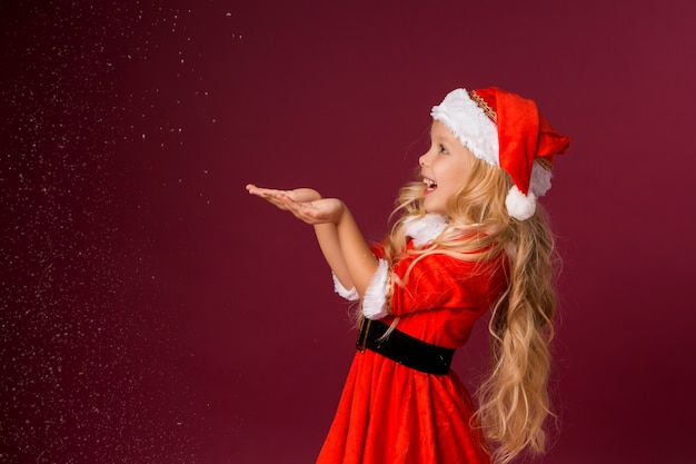 Mała blondynki dziewczyna w Santa kostiumu łapie śnieg