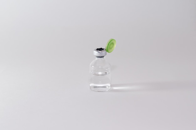 Mała butelka bez napisów i etykiet ze szczepionką stoi na białym stole