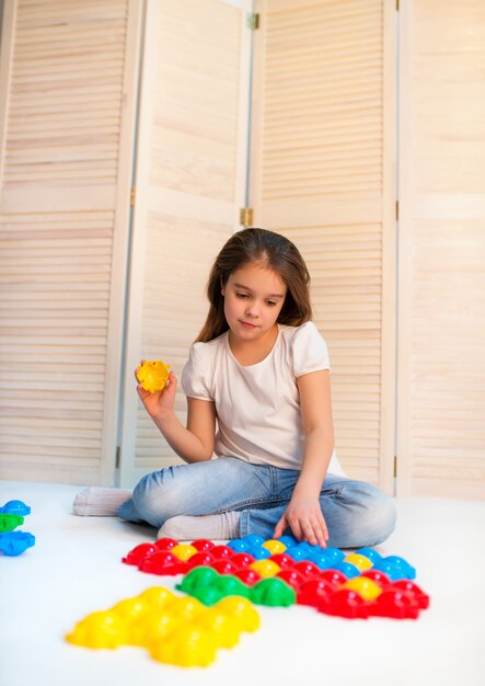 Mała ciekawa dziewczyna układa plastikowe puzzle