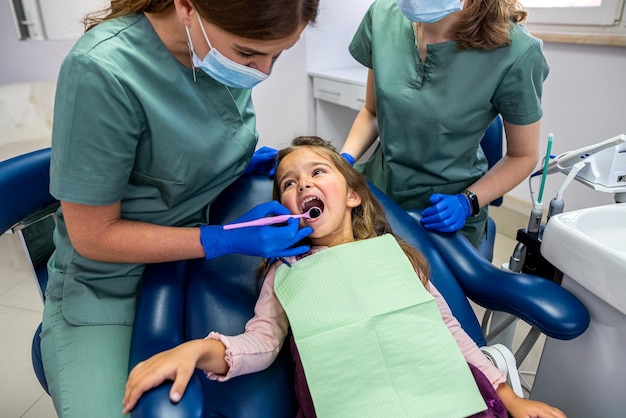 Mała cierpliwa dziewczynka przyszła do dentysty na umówioną wizytę. Koncepcja leczenia stomatologicznego dziecka