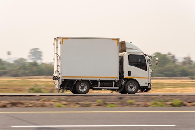 Zdjęcie mała ciężarówka jazdy na autostradzie mała biała ciężarówka dostawcza szybko porusza się po dystrybucji drogowej ekspresowa dostawa biznesowa
