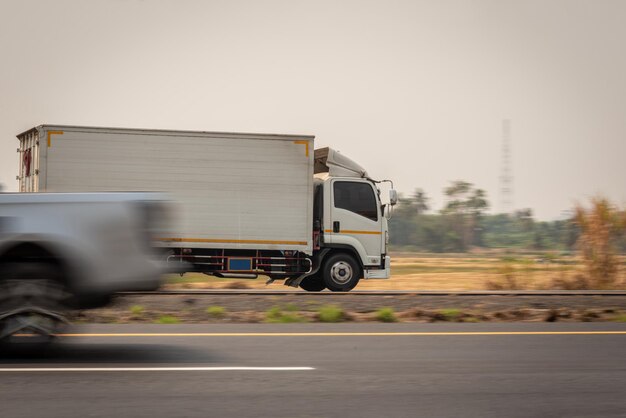 Zdjęcie mała ciężarówka jazdy na autostradzie mała biała ciężarówka dostawcza szybko porusza się po dystrybucji drogowej ekspresowa dostawa biznesowa