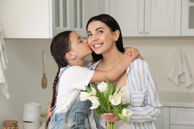 Mała córka gratuluje mamie w kuchni w domu Szczęśliwego Dnia Matki