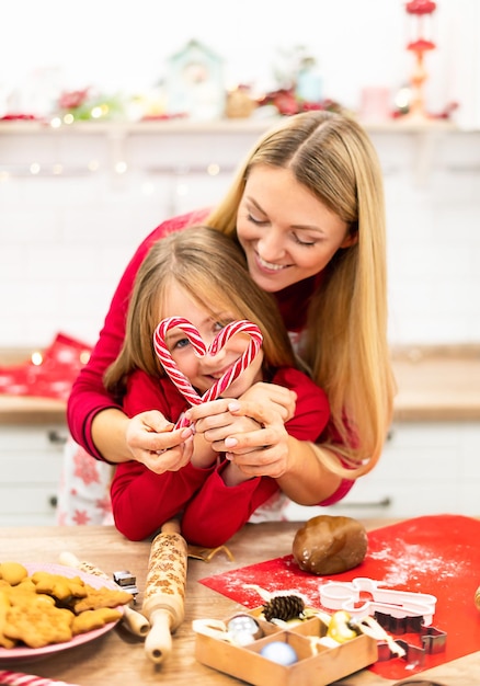 Mała córka i mama zrobiły kształt serca ze świątecznych cukierków w kuchni, robiąc zabawę