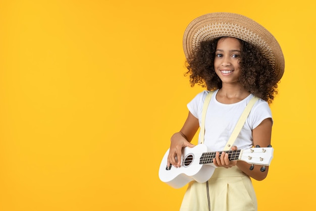 Mała dziewczyna w kapeluszu grająca na ukulele odizolowana na białym tle