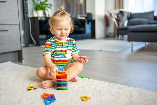 Mała dziewczynka bawi się kolorowymi magnetycznymi plastikowymi klockami zestaw w domu dziecko gra w gry edukacyjne e