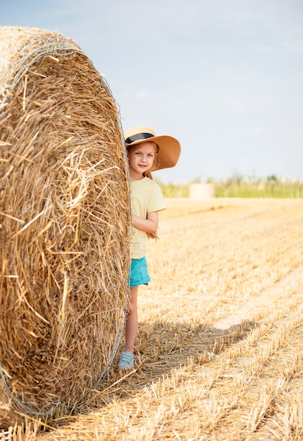 Mała dziewczynka bawi się na polu pszenicy w letni dzień
