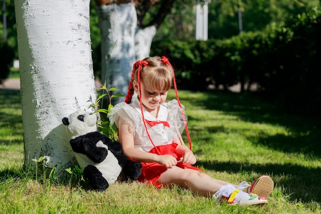 Mała Dziewczynka Bawi Się Zabawką Pandą W Parku W Lecie. Zdjęcie Wysokiej Jakości