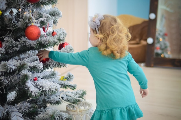 Zdjęcie mała dziewczynka bawiąca się w pokoju z dekoracją świąteczną i choinką