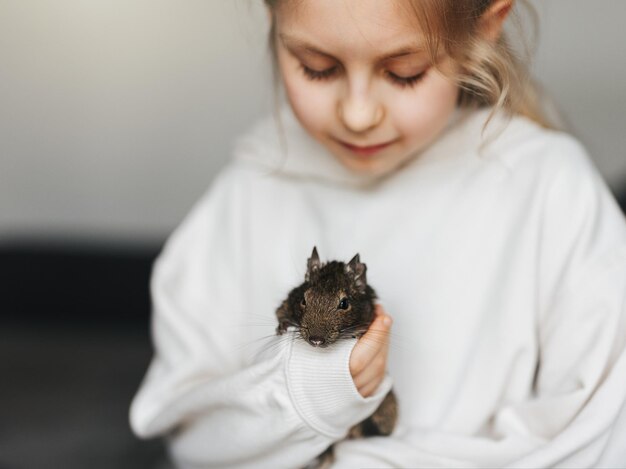 Mała dziewczynka bawiąca się z małą wiewiórką degu