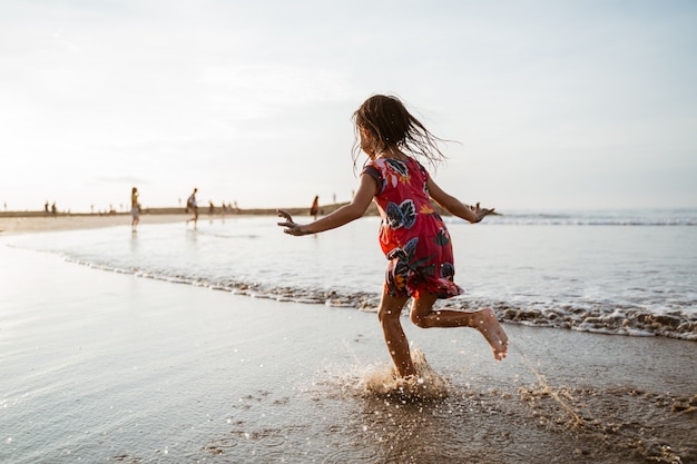 Mała dziewczynka bieg na plaży podczas gdy bawić się z wodą
