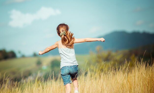 Mała dziewczynka biegnie przez łąkę