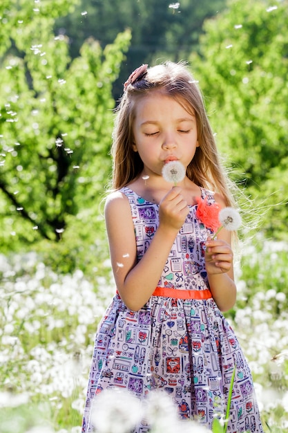 Mała dziewczynka cieszy się Dandelion's pole lub zieloną łąkę w wiosna słonecznym dniu.