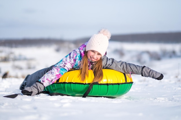 Zdjęcie mała dziewczynka cieszy się snow tubing przy słoneczną pogodą