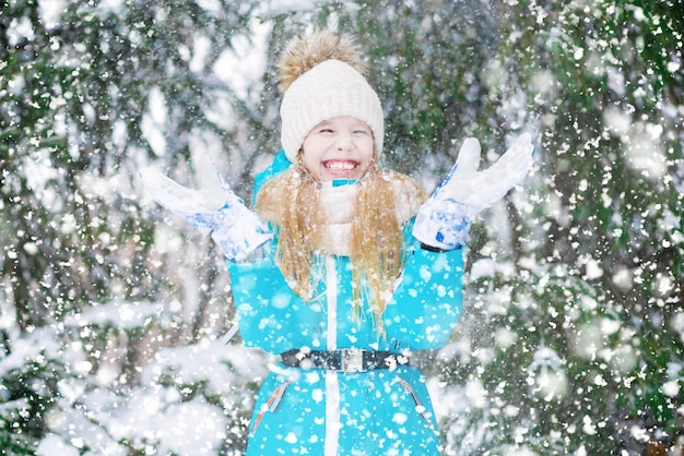 Mała dziewczynka dobrze się bawi zrzucając śnieg w lesie