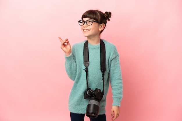 Mała dziewczynka fotograf na białym tle, chcąc zrozumieć rozwiązanie, podnosząc palec