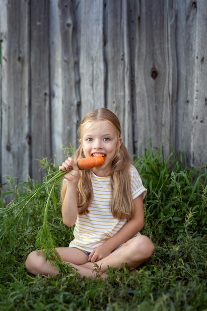 Mała dziewczynka gryzie świeżą marchewkę Świeża zdrowa żywność organiczna