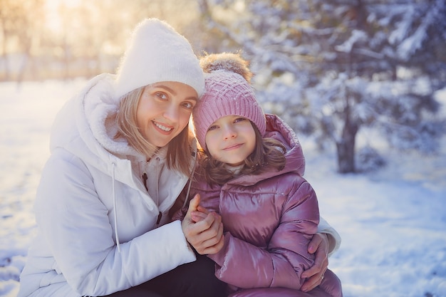 Mała dziewczynka i jej mama bawią się na świeżym powietrzu w słoneczny zimowy dzień