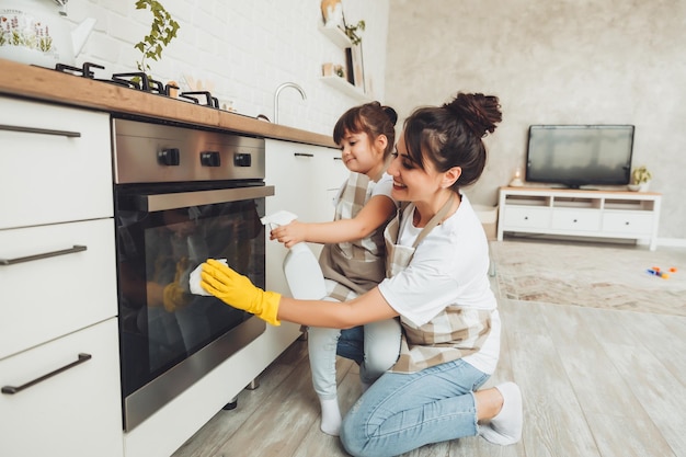 Mała Dziewczynka I Jej Mama Sprzątają Kuchnię Kobieta Z Dzieckiem Wycierają Piekarnik W Kuchni Sprzątają Dom Pomagając Mamie