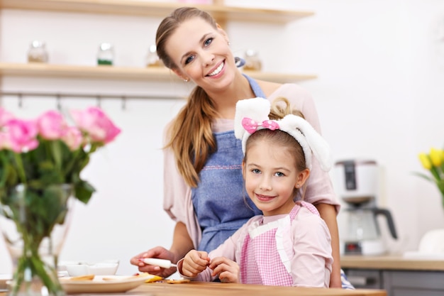 mała dziewczynka i jej mama w fartuchach bawią się w kuchni